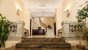 A grand marble staircase leading to a reception area with a modern chandelier and wall sconces. - Atrium Hotel Ateneu City Center (Bucharest)