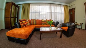 A modern living room with a sectional sofa, a coffee table, and a leather armchair. - Atrium Hotel Ateneu City Center (Bucharest)