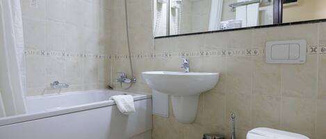 Un baño con bañera, lavabo, inodoro y espejo.