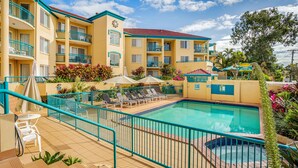 Un hotel con piscina, varios balcones y zonas de estar al aire libre.