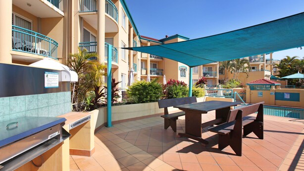 Un patio con una parrilla, mobiliario exterior y una piscina.