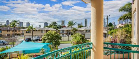Un balcón con vistas a una zona residencial, con edificios y coches aparcados.