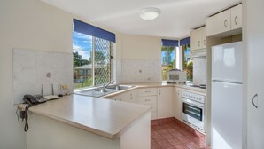 Una cocina con mostrador, pileta, estufa y refrigerador.