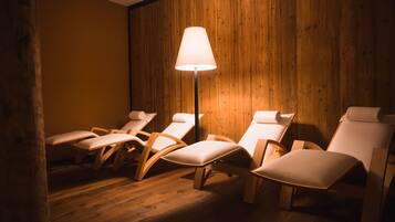 Ein Zimmer mit Holzwandverkleidung, einer Stehlampe und mehreren weißen Loungesesseln.