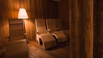 A room with wooden walls and floors, featuring three wooden chairs and a floor lamp.
