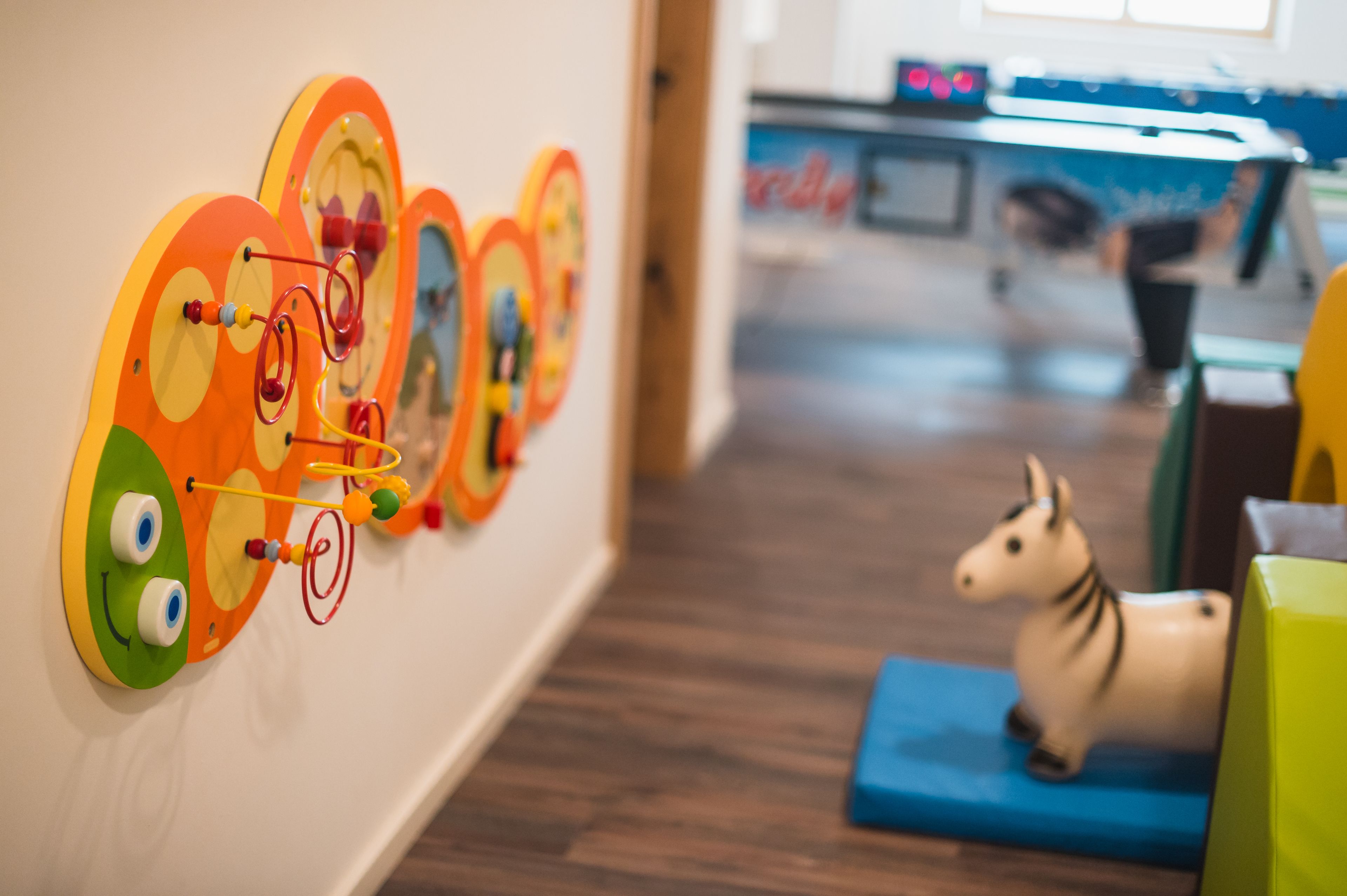A children's play area with colorful, abstract wall decorations and a small horse figurine on a blue mat.