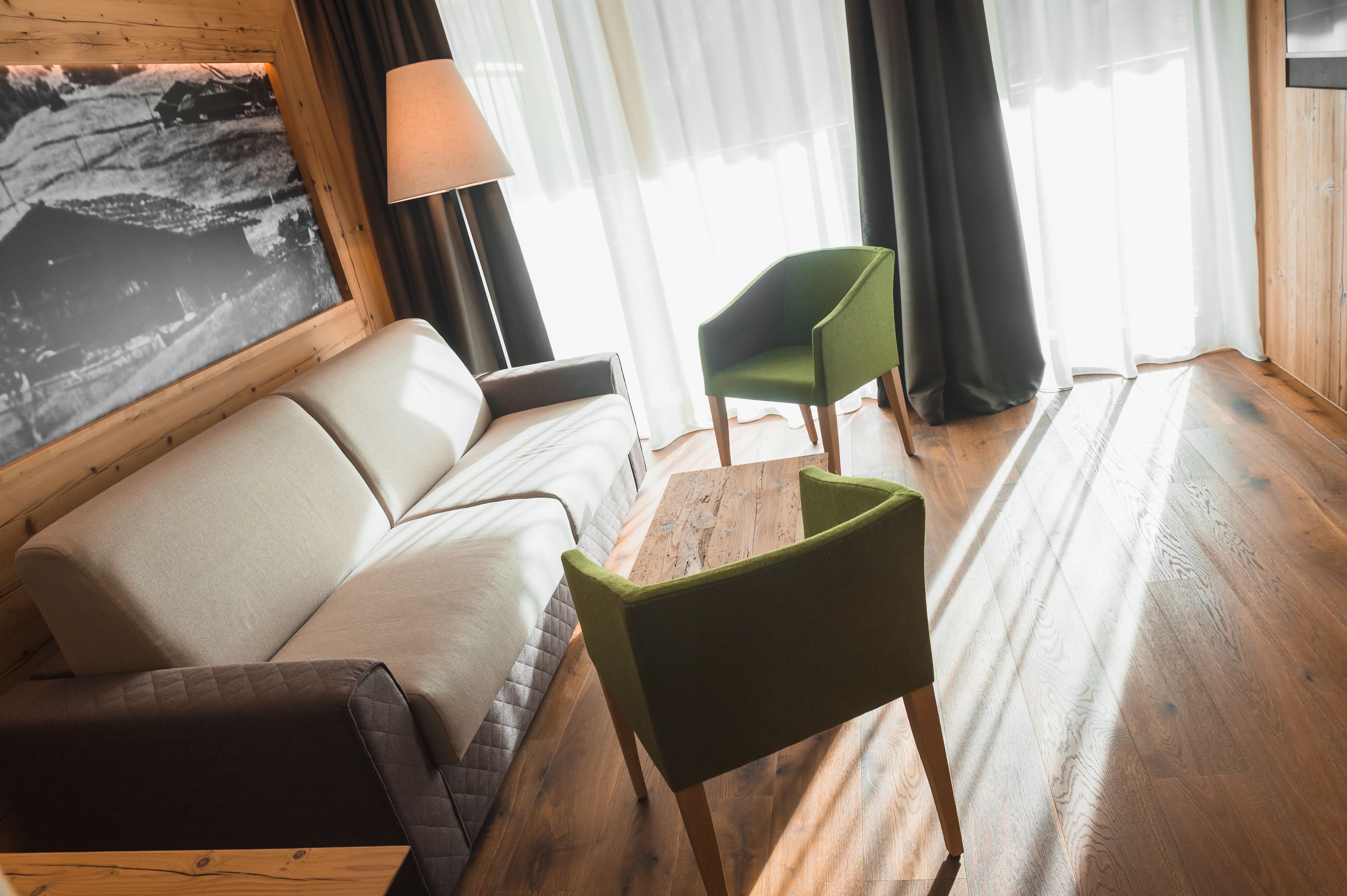 A room with a sofa, a green chair, a wooden coffee table, and a lamp.