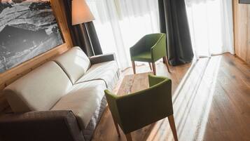 A room with a sofa, a green chair, a wooden coffee table, and a lamp.
