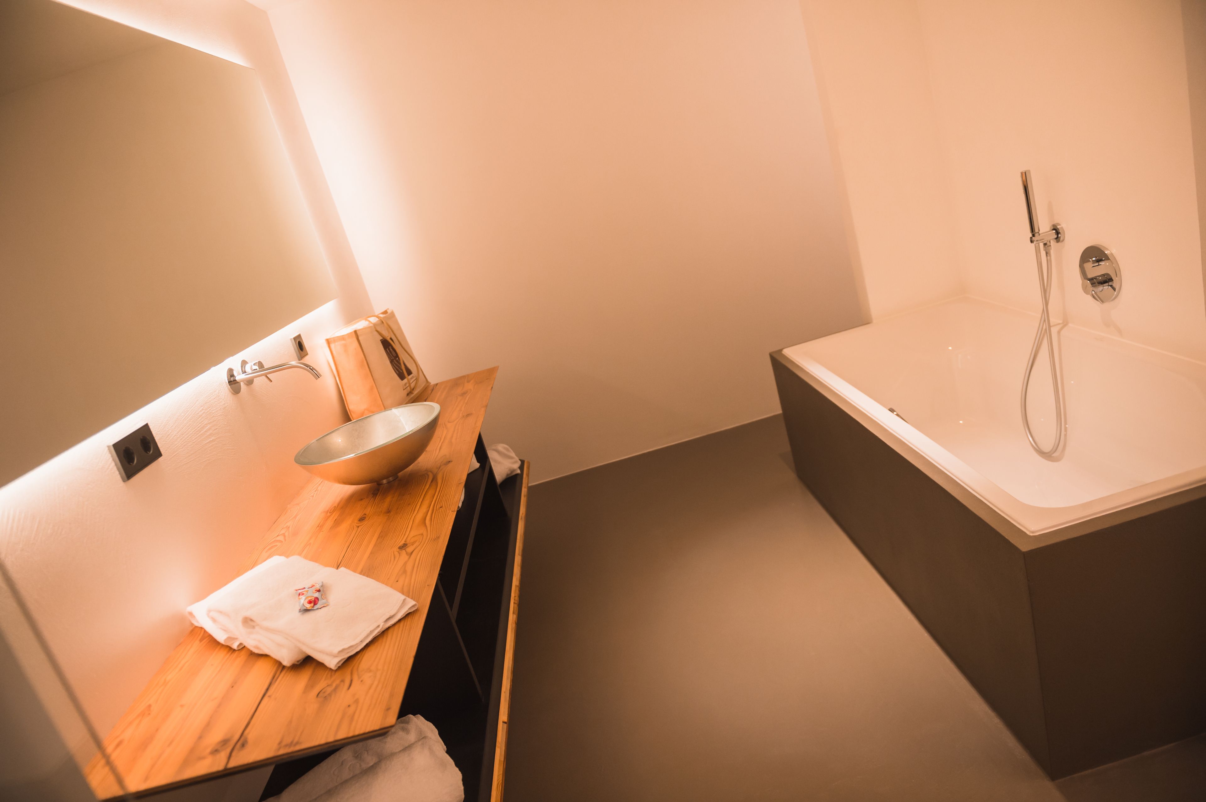 Une salle de bain moderne avec un meuble-lavabo en bois, un évier et une baignoire.