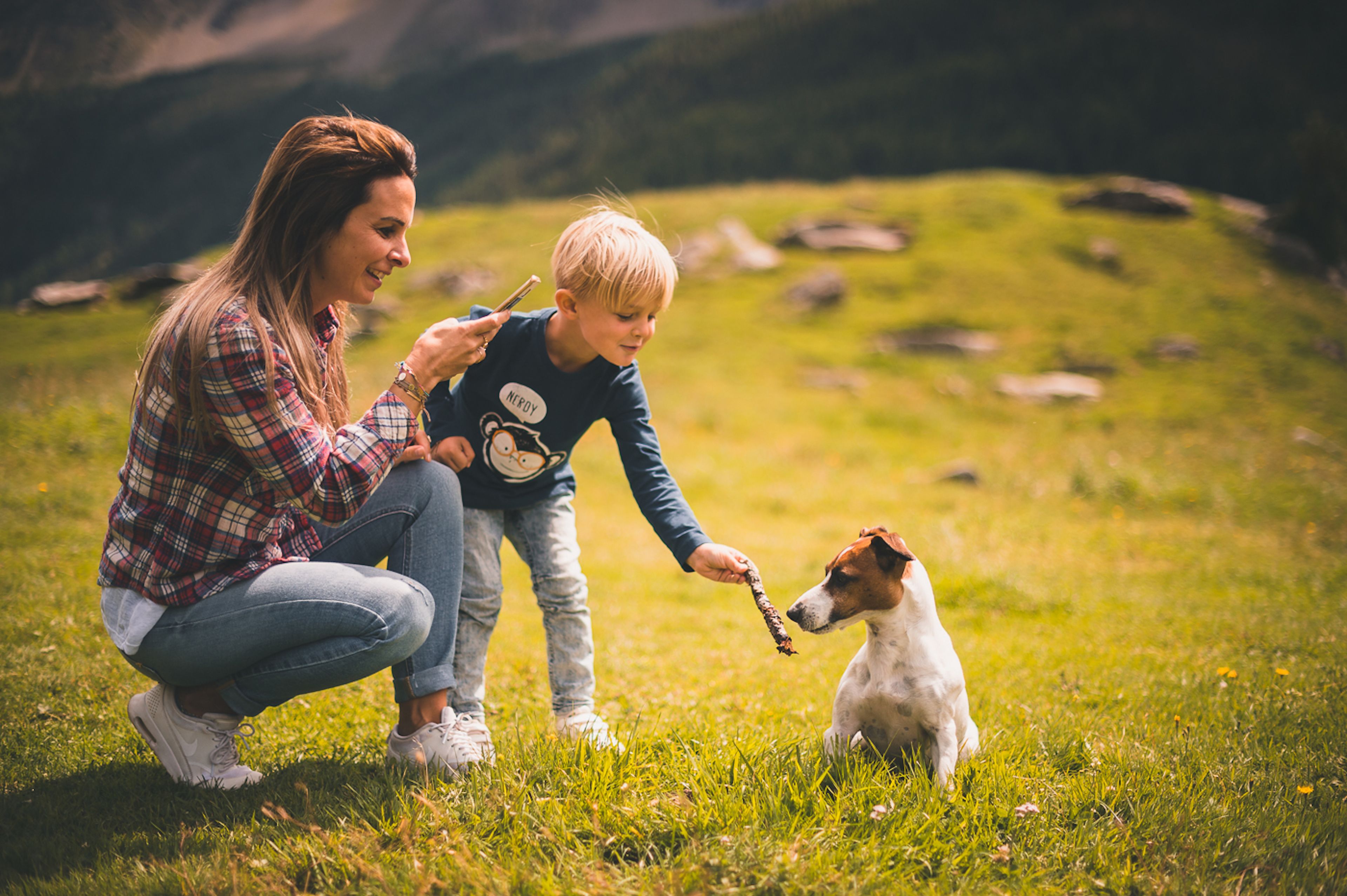 Iemand knielt op het gras met een hond en een kind.