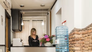 A reception area with a receptionist, a water dispenser, a large water bottle, and a purple chair.