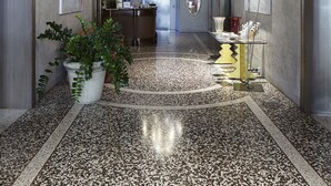 A hallway with a large chandelier, potted plants, and artwork on the walls. - Albergo Cappello (Ravenna)