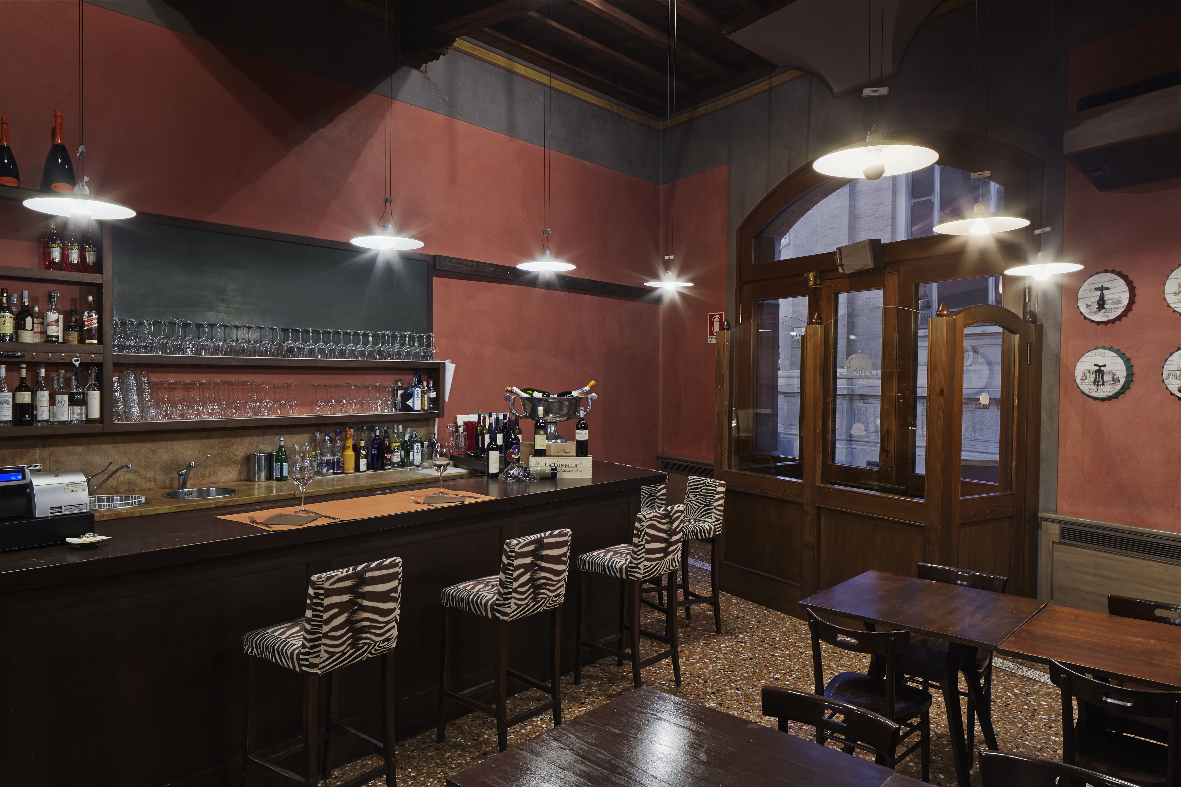 Zona de bar con mostrador, taburetes y un área de estar con mesas y sillas.