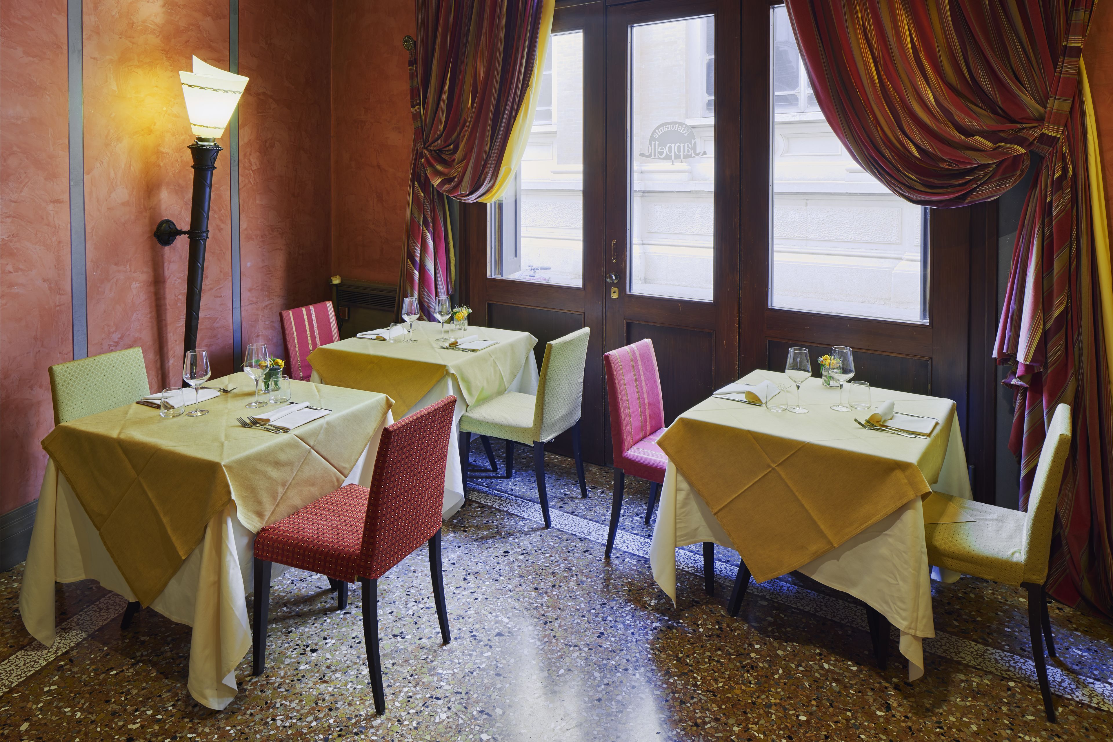 A restaurant interior with tables set for dining, chairs, and a floor with a speckled pattern.