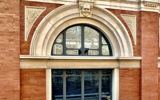 A building with a large arched window and a smaller window below it.