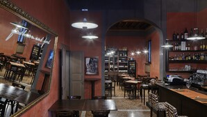 A bar area with a mirrored wall, wooden furniture, and a variety of bottles on shelves. - Albergo Cappello (Ravenna)