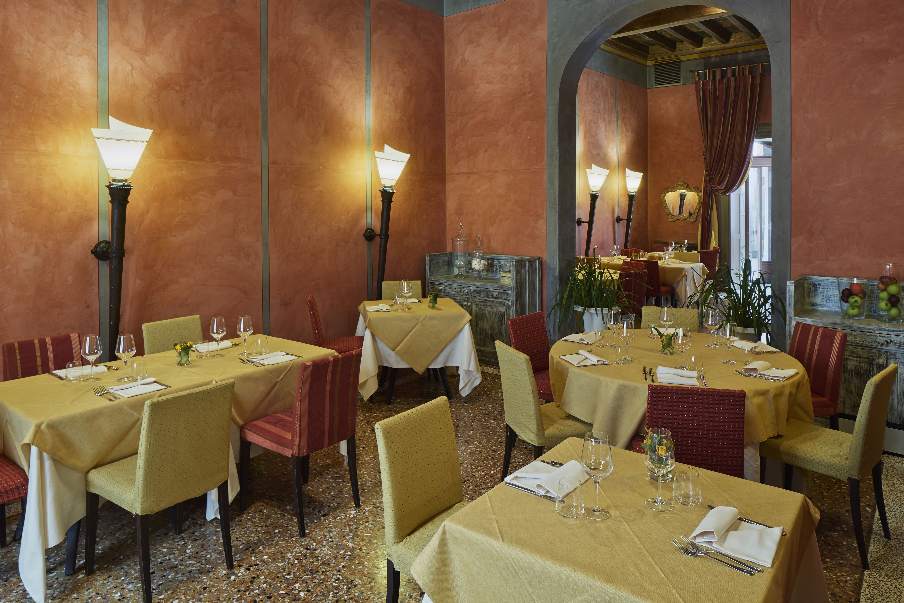 Un restaurant avec de nombreuses tables dressées pour le service, chacune étant équipée de chaises et de couverts.