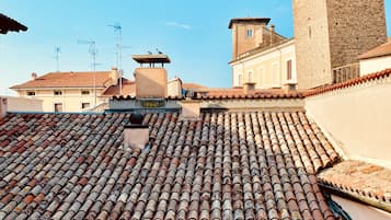 Una azotea con tejas de terracota, una torre de piedra y un edificio con techo plano.