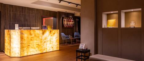 A hotel reception area with a marble counter, seating area, and a bar.