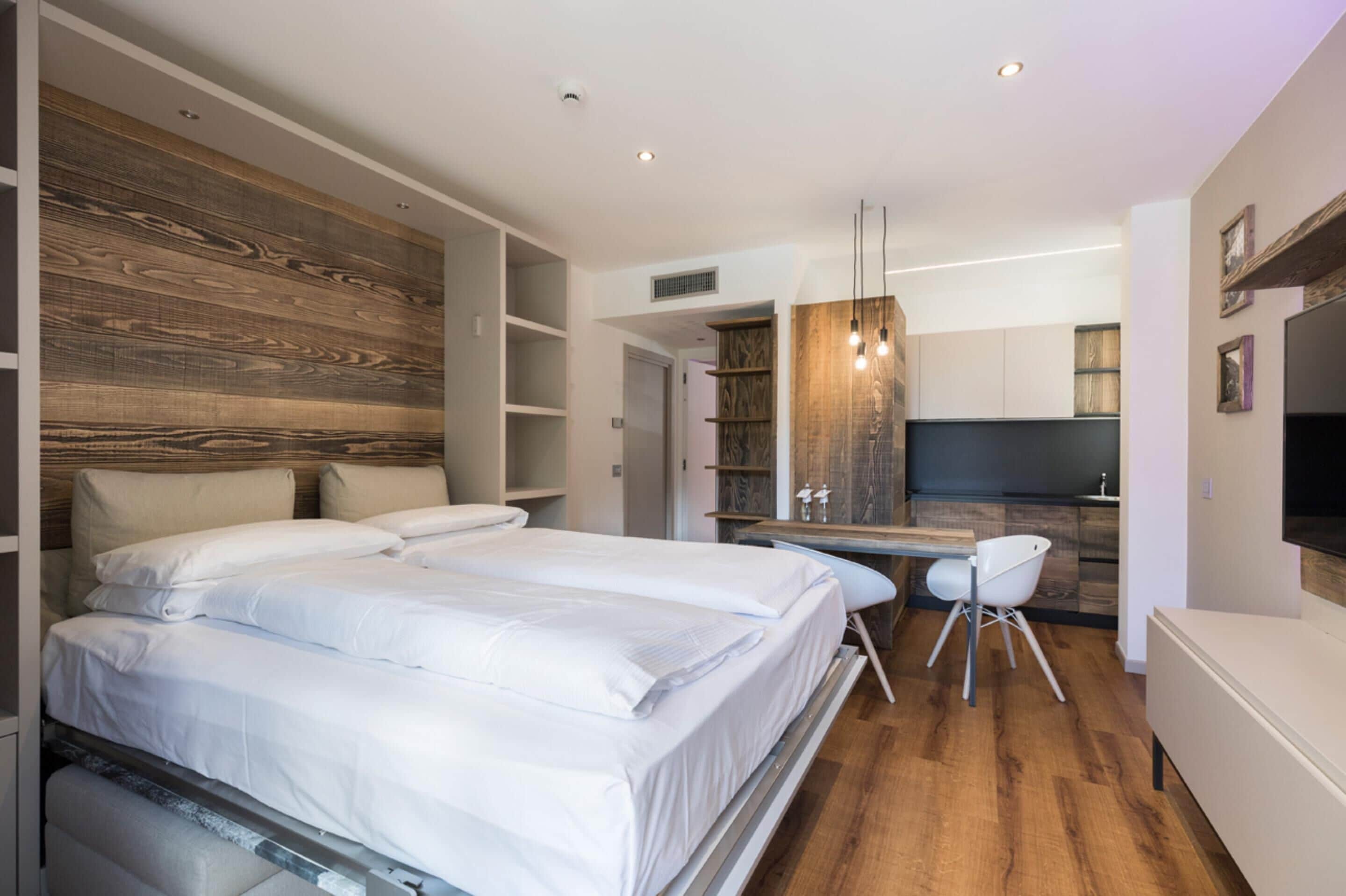 Ein modernes Schlafzimmer mit einem großen Bett, einem Schreibtisch und einer Küchenzeile.