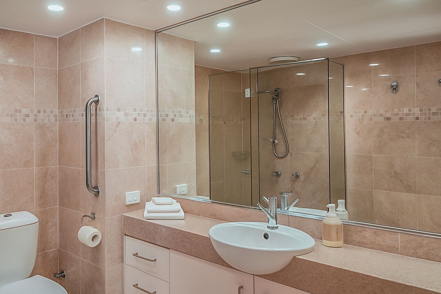 A modern bathroom with a glass shower enclosure, a white sink, and a large mirror.
