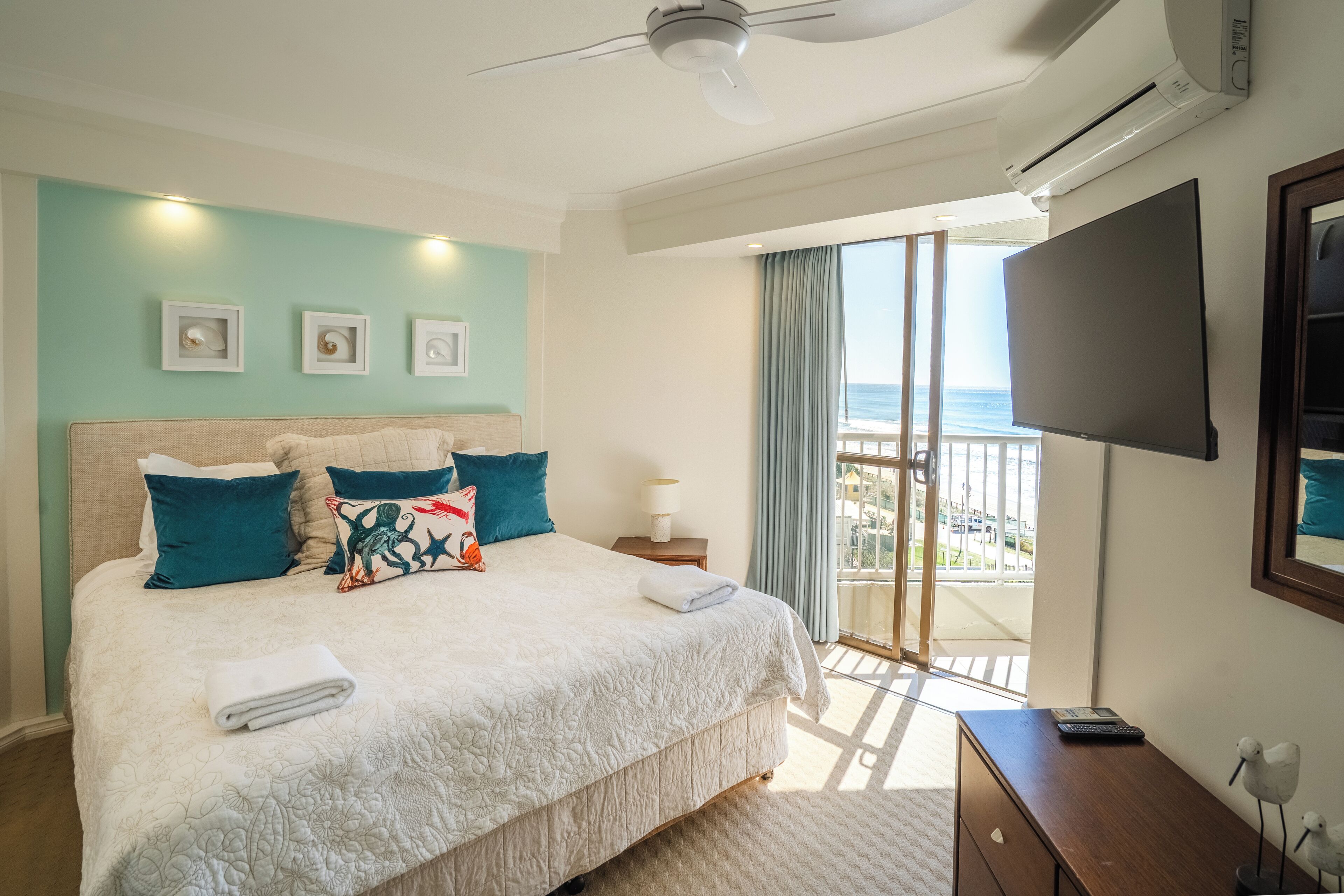 Una camera da letto con un letto grande, una televisione, una scrivania e un balcone con vista.