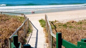 A beach pathway leading to the shore with a wooden fence on either side. - The Breakers (Surfers Paradise)