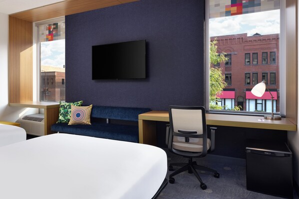A modern hotel room with a large bed, a desk, a chair, a TV mounted on the wall, and a window with a view of buildings. - Aloft by Marriott Minneapolis (Minneapolis)