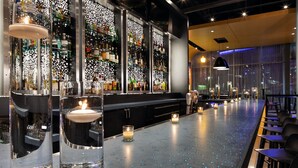A bar area with a long counter, candles, and shelves of bottles. - Aloft by Marriott Minneapolis (Minneapolis)