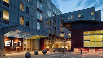 A hotel with a modern facade, a covered entrance, and a parking area.