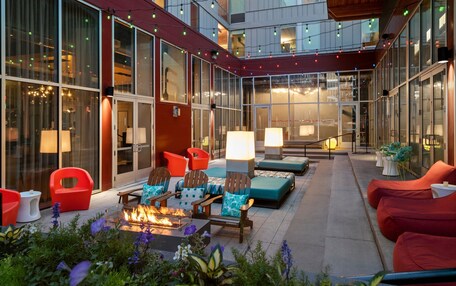 An outdoor patio area with seating, a fire feature, and a view of the building's interior.