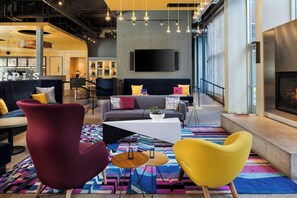 A modern lounge area with a sofa, armchairs, a coffee table, and a flat-screen TV mounted on the wall. - Aloft by Marriott Minneapolis (Minneapolis)