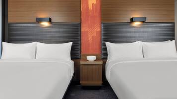 A hotel room with two beds, a nightstand with a lamp, and a decorative wall panel.