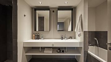 A modern bathroom with a double sink, two mirrors, a vanity, and a bathtub.