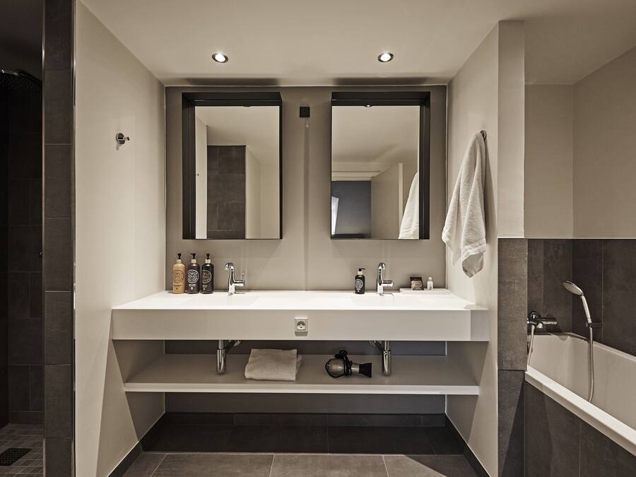 A modern bathroom with a double sink, two mirrors, a vanity, and a bathtub.