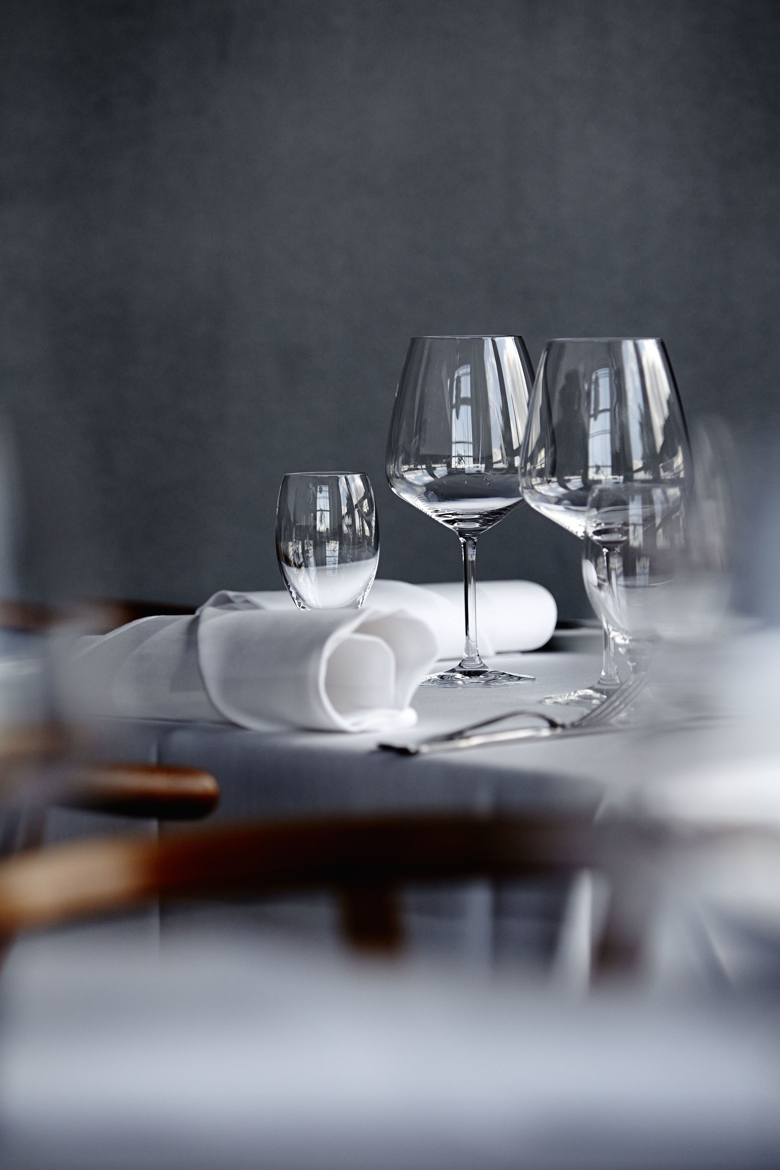 Una mesa con tres copas de vino y una servilleta blanca enrollada.