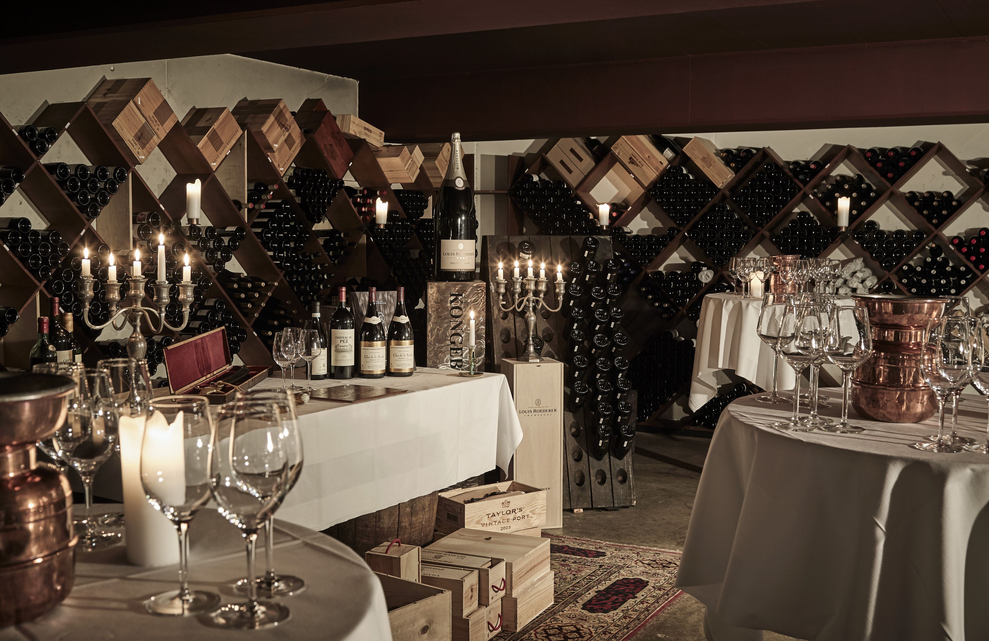 Una bodega con estanterías de madera llenas de botellas y copas de vino.