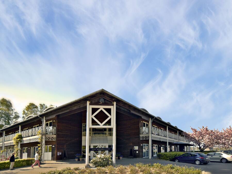 A hotel with a wooden facade, multiple balconies, and a sign indicating it is a hotel.