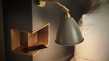 A wall-mounted lamp with a smartphone on a wooden shelf.