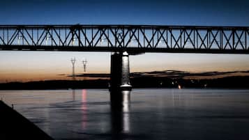 Een nachtzicht van een brug over een rustig waterlichaam, met een silhouet van een toren op de achtergrond.