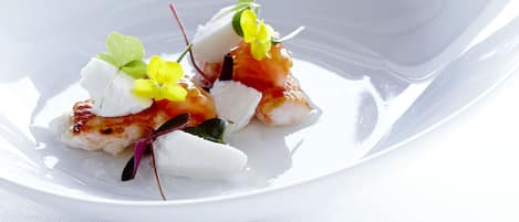 Un plato blanco con un guiso de mariscos adornado con flores y hierbas.