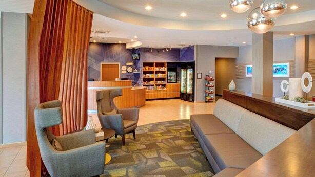 A modern hotel lobby with a reception desk, seating area, and a refreshment bar. - SpringHill Suites St. Louis Brentwood (Brentwood)