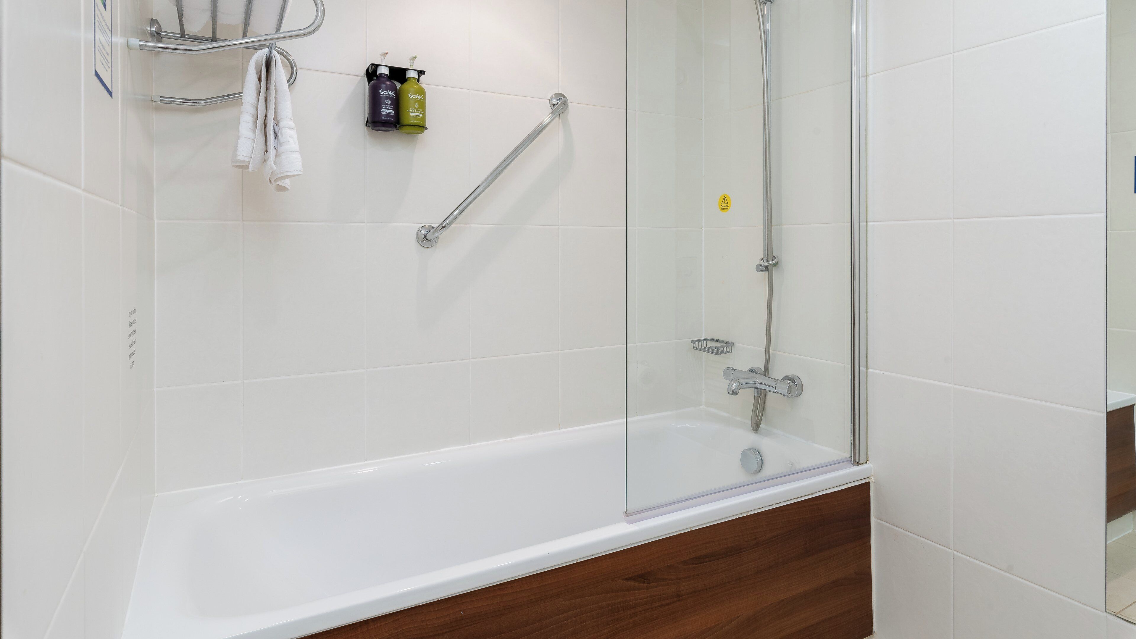 A modern bathroom with a glass-enclosed shower, a white bathtub, and a wooden vanity.