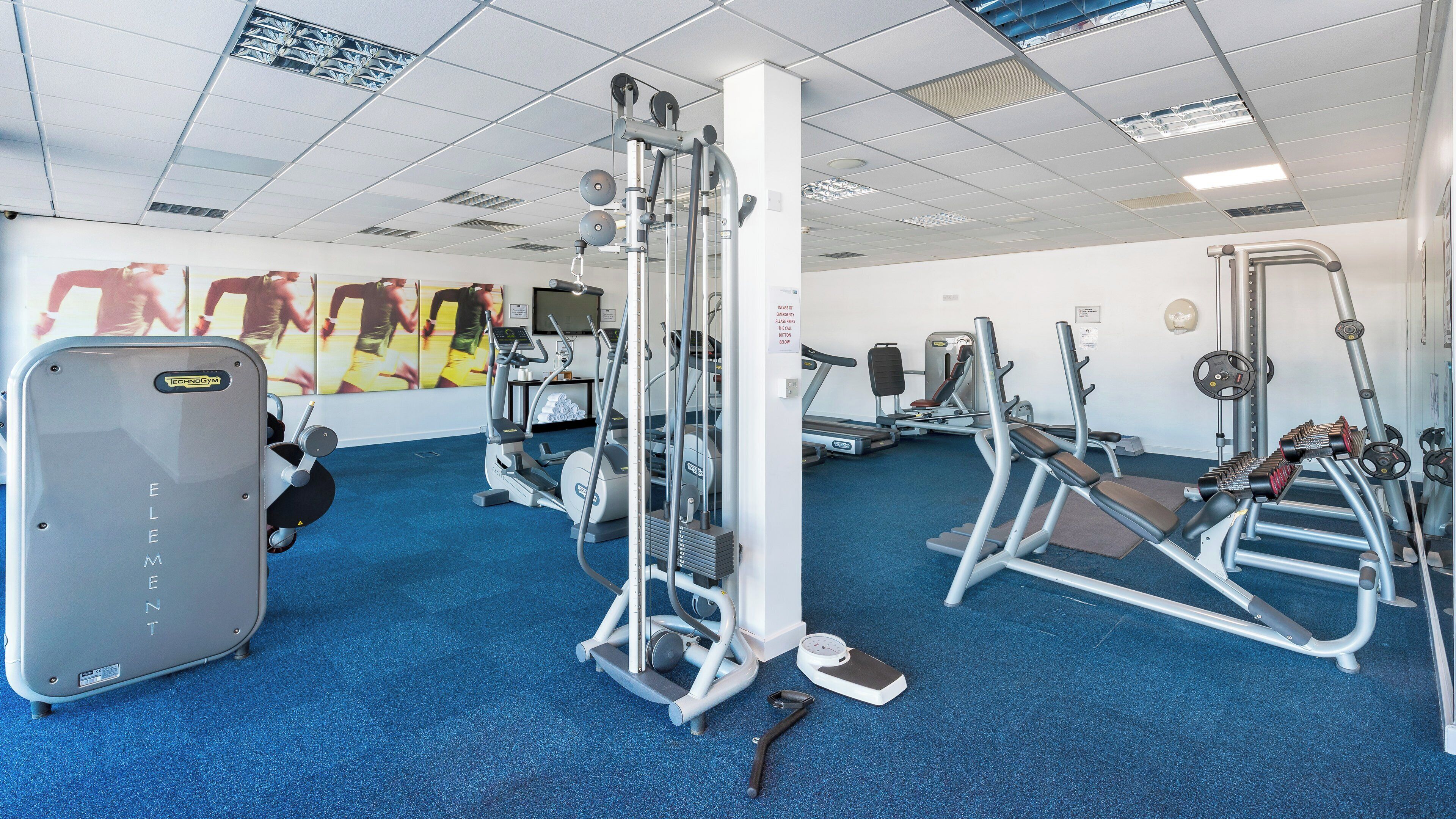 A gym with various exercise equipment, including a treadmill, elliptical, and weight machines.