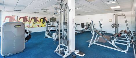 A gym with various exercise equipment, including a treadmill, elliptical, and weight machines.