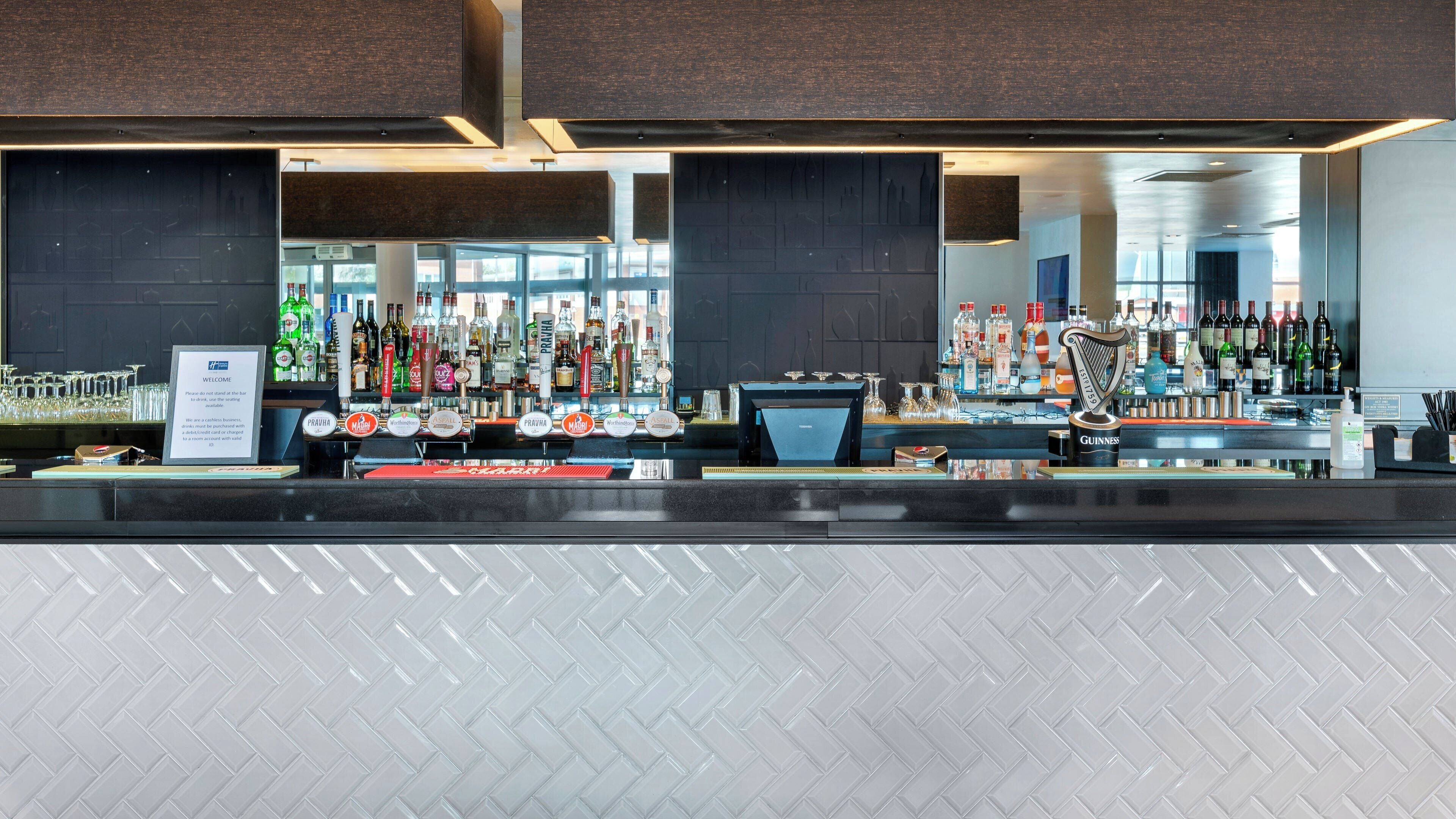 A bar area with a variety of liquor bottles, a Guinness tap, and a welcome sign.