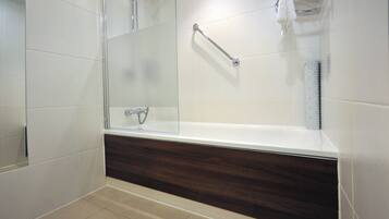 A modern bathroom with a glass-enclosed shower, a wooden vanity, and a white tiled floor.