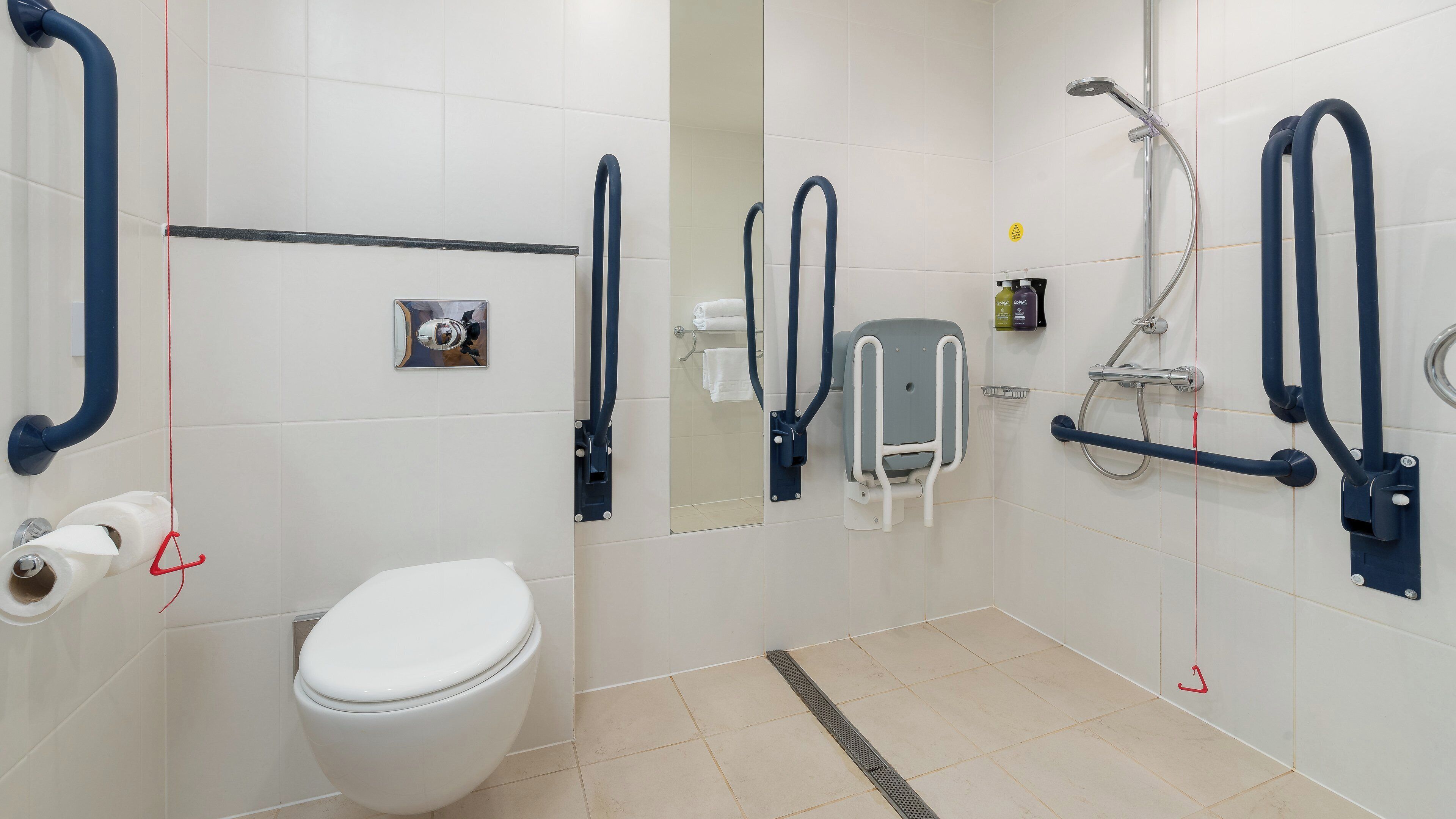 A modern bathroom with a white toilet, a shower area, and grab bars.
