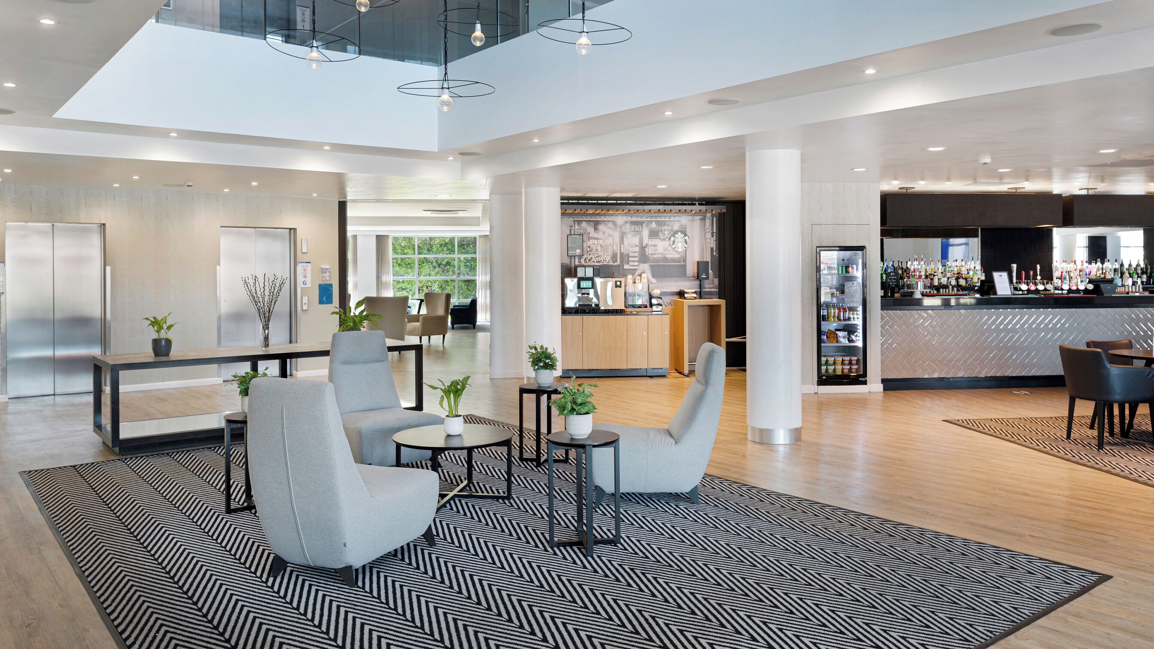 Een moderne hotellobby met zithoeken, een bar en een receptiebalie.