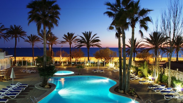 A pool area with lounge chairs and palm trees, overlooking the ocean. - Hotel HSM Golden Playa (Palma de Mallorca)